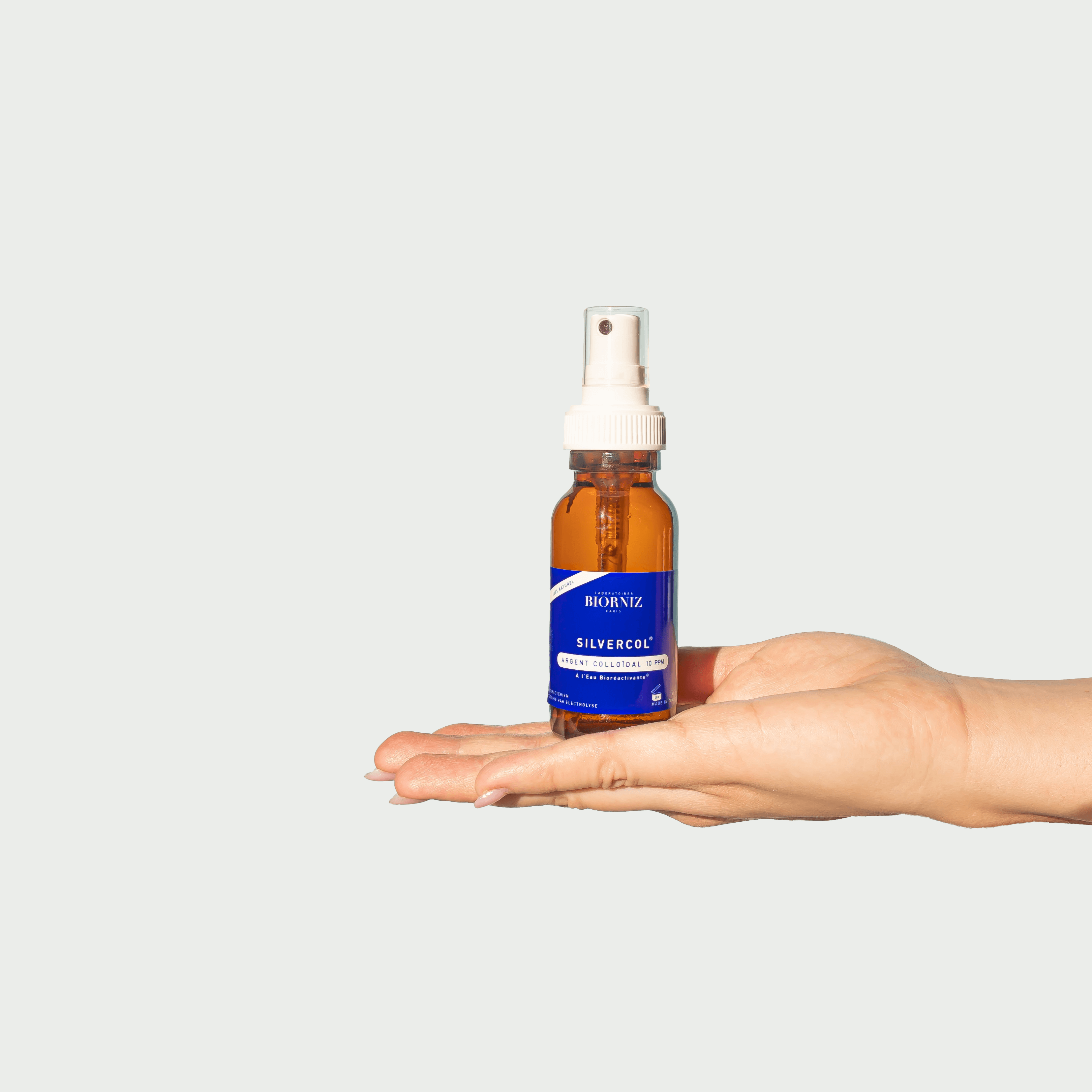 Femme qui porte sur sa main un spray en verre ambré d'argent colloidal 10 ppm 